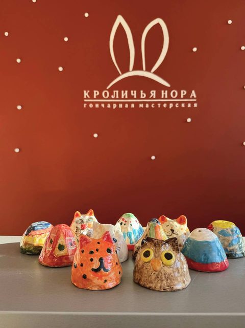 Ряд глиняных фигурок-кошек, расписанных школьниками